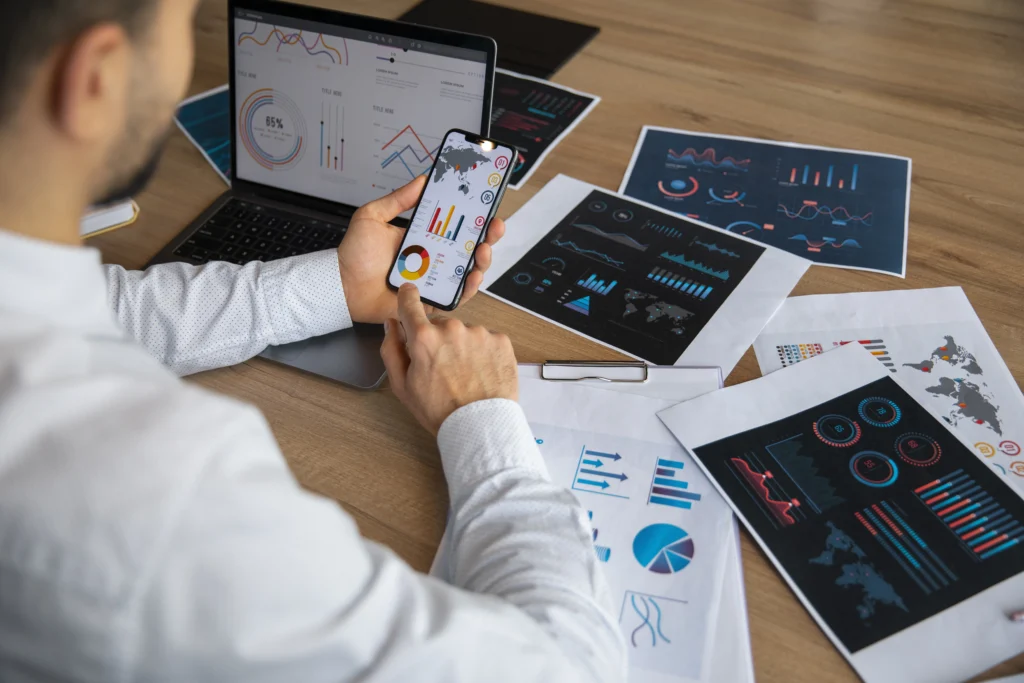 Person analyzing UI/UX charts and mobile prototypes